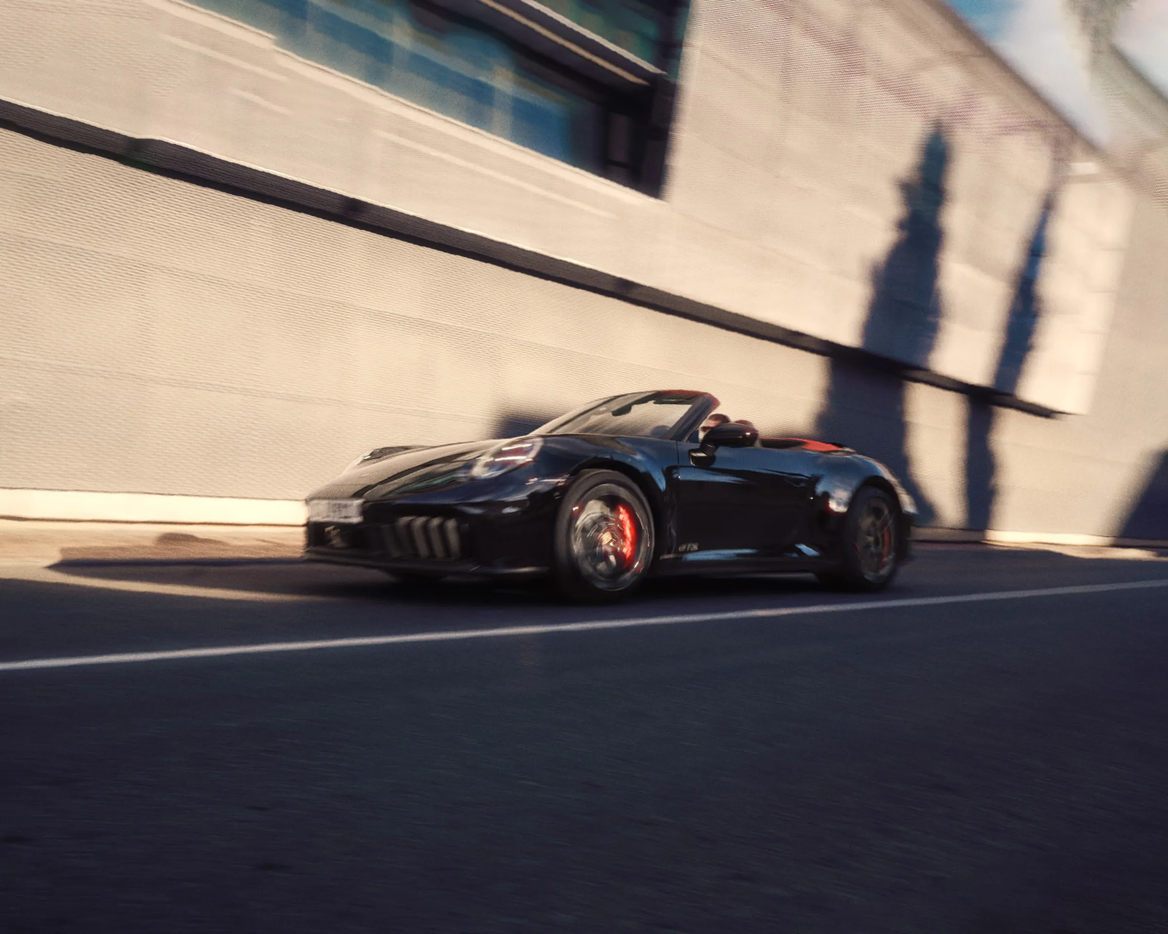 Une Porsche 911 noire décapotable sur la route