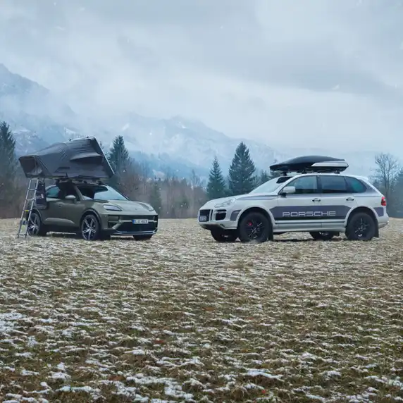 Deux Porsche Cayenne avec des accessoires tels qu’un coffre de toit, stationnées dans un paysage montagneux.